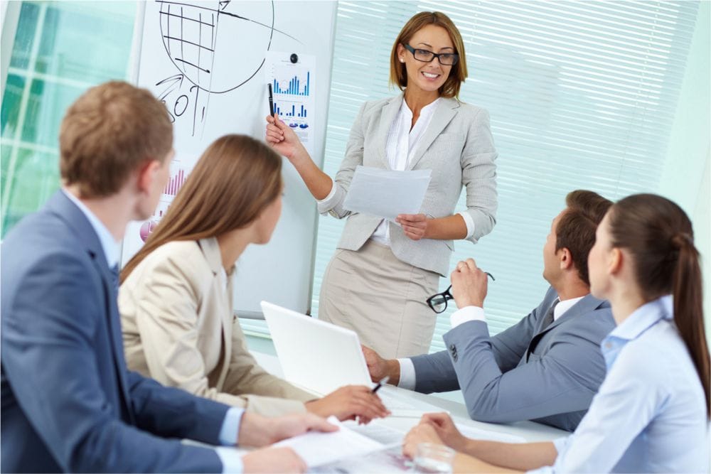 Crédit de formation continue : une femme avec un employé montre des statistiques au tableau.